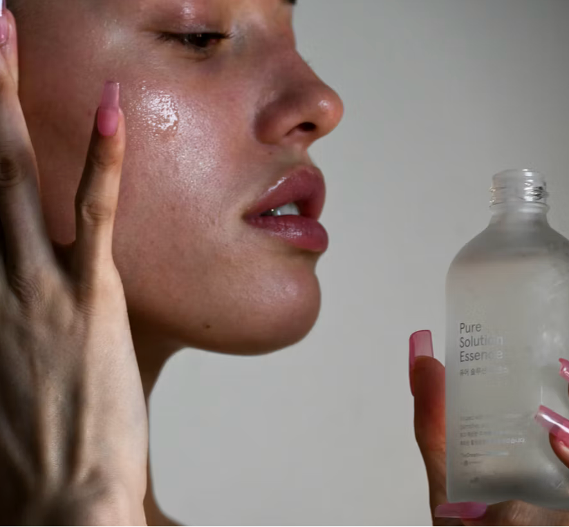Person applying a skincare product to their face with a bottle of 'Pure Solution' in the foreground.
